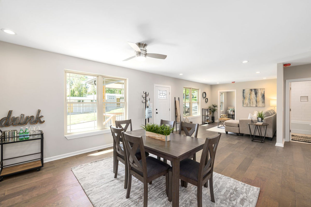 Open-plan dining and living area with separate pale rugs beneath the table and seating