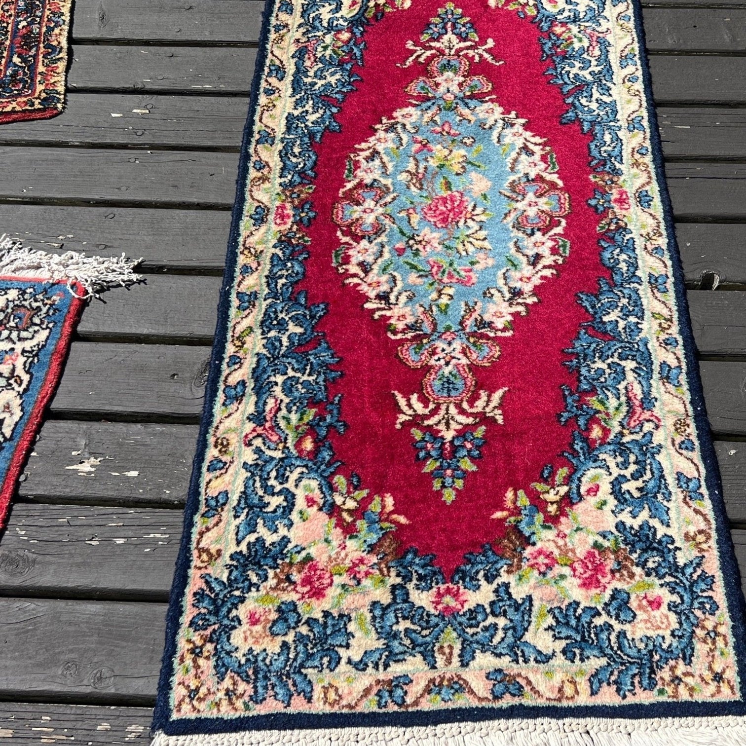 Floral Kerman rug catalogued as circa 1920, pictured on a deck; date is a seller attribution