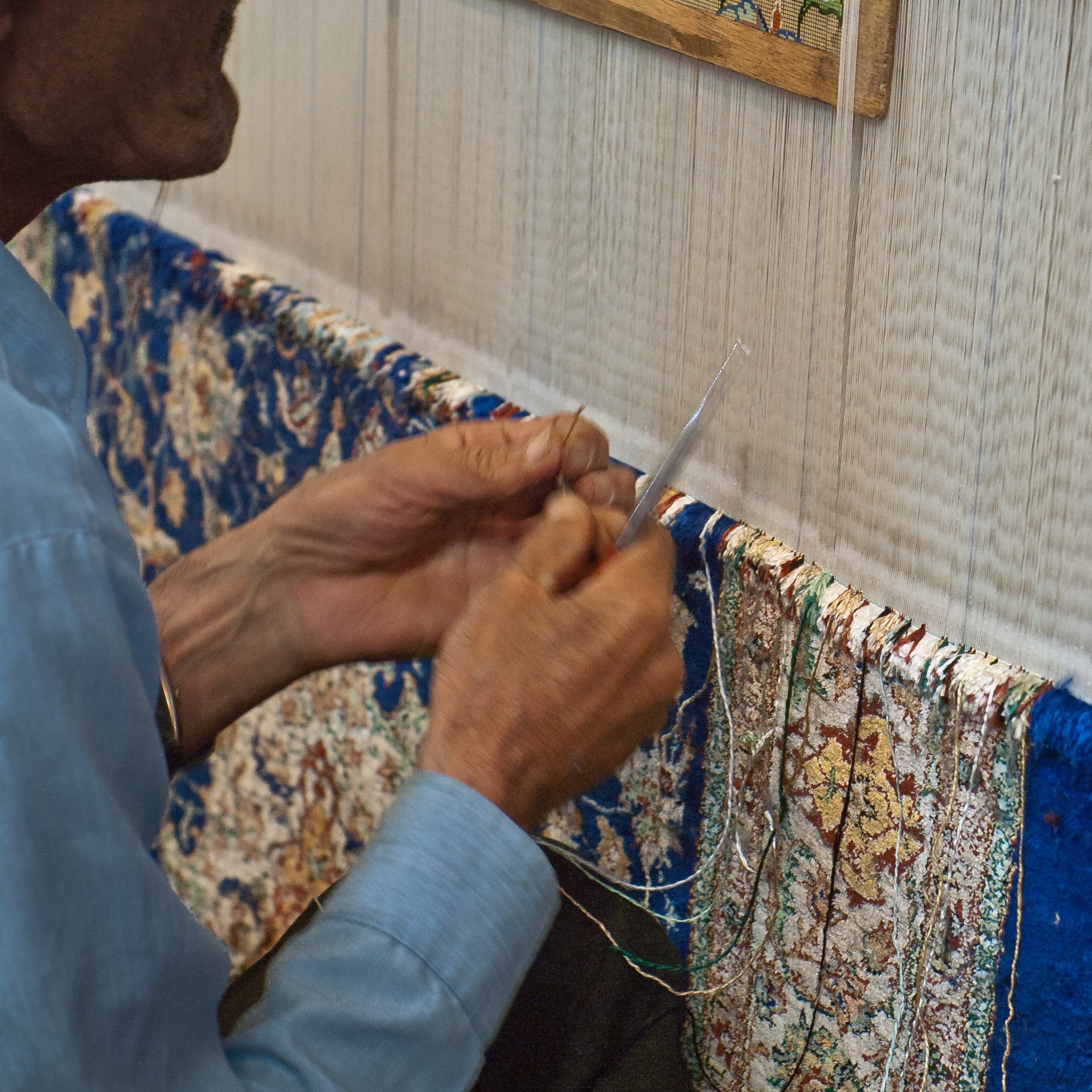 Carpet weaver in Isfahan following a gridded floral design at the loom