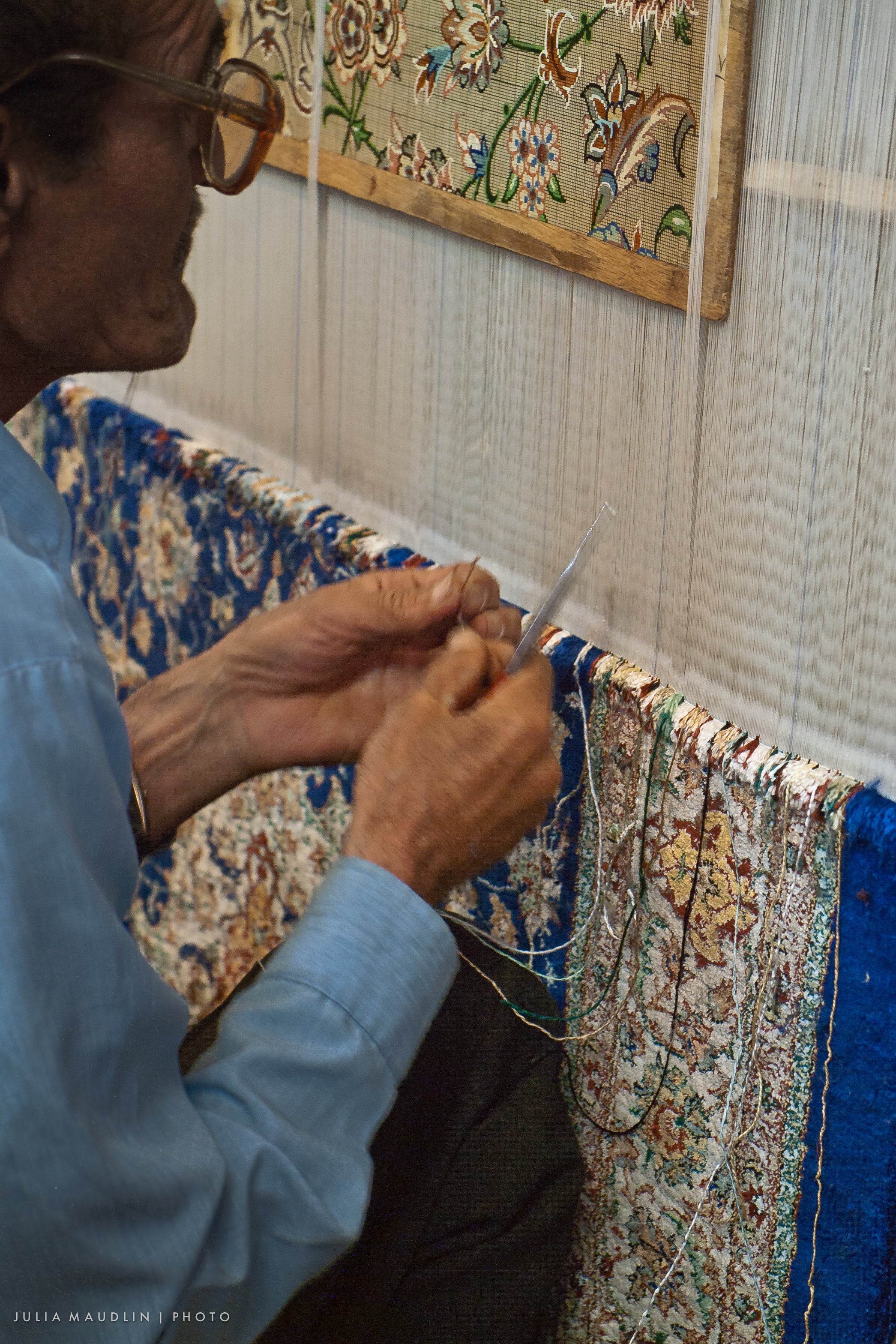 Carpet weaver in Isfahan following a gridded floral design at the loom