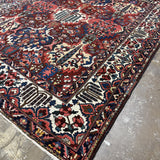 Diagonal view of Bakhtiari rug showing the ivory border, multicolored floral motifs and corner fringe.