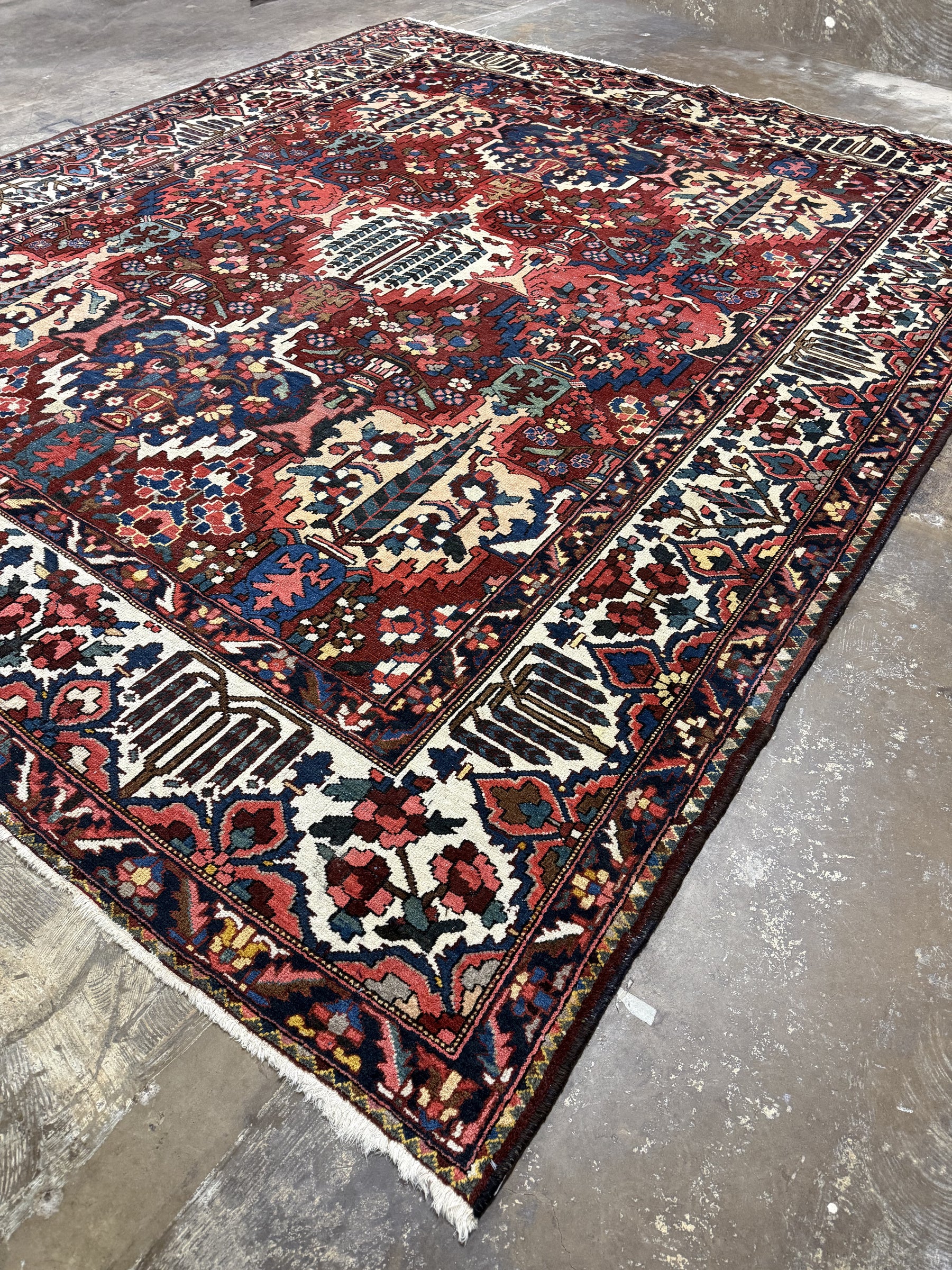 Diagonal view of Bakhtiari rug showing the ivory border, multicolored floral motifs and corner fringe.