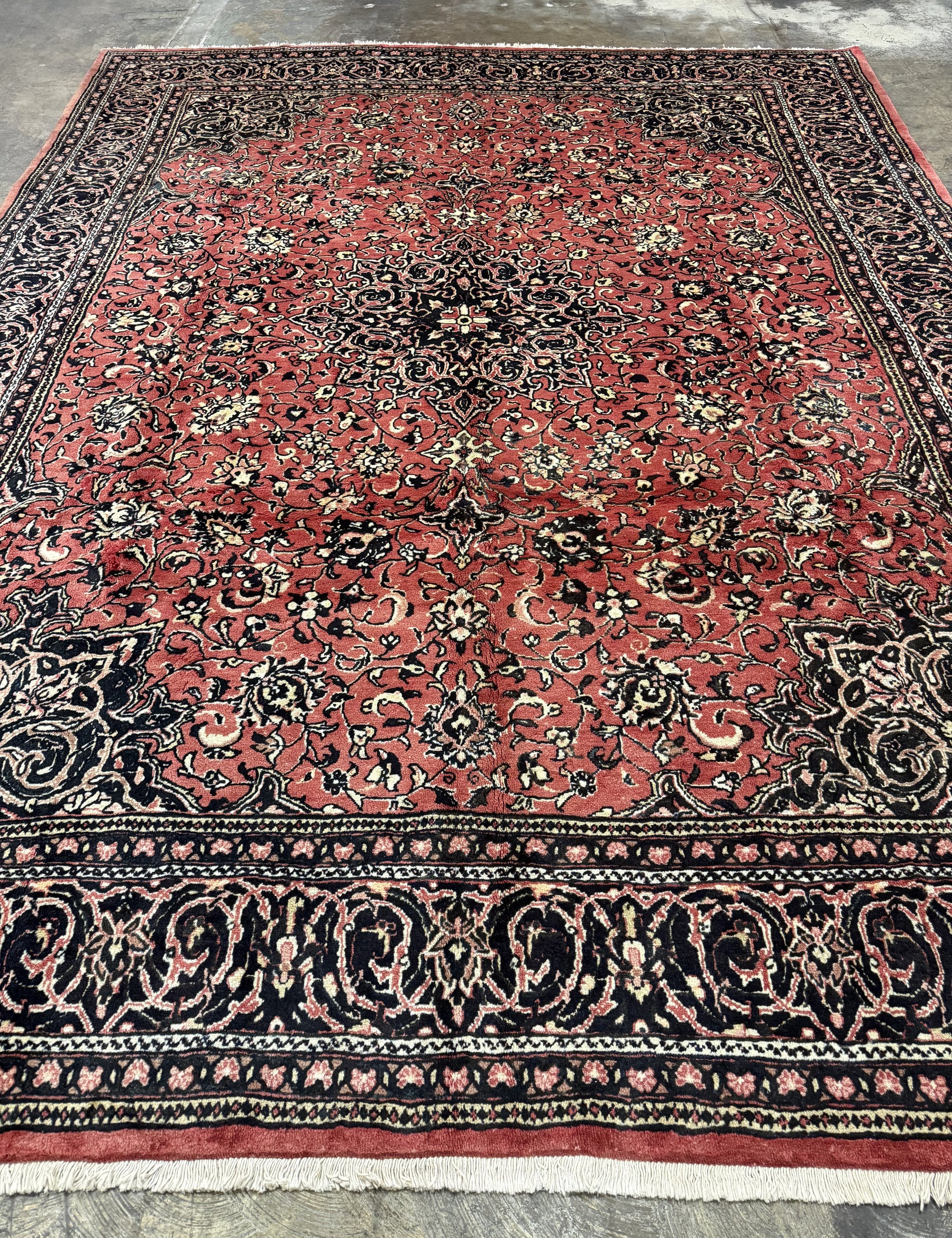 Sarough hand-knotted wool rug, lengthwise view, showing a red floral field with a central medallion and dark navy border.