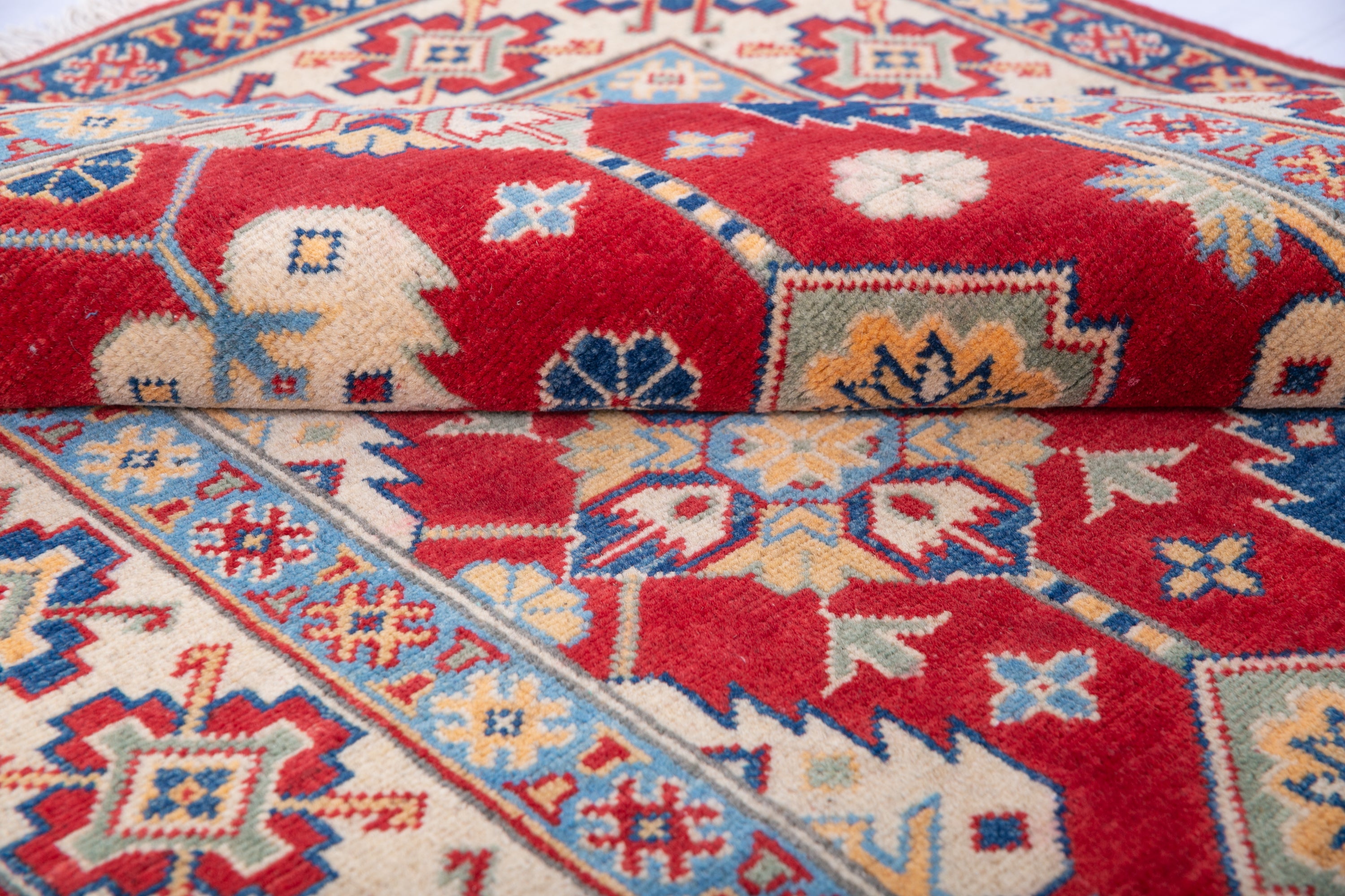Folded edge and wool pile of red & ivory Kazak-inspired wool rug 21997.