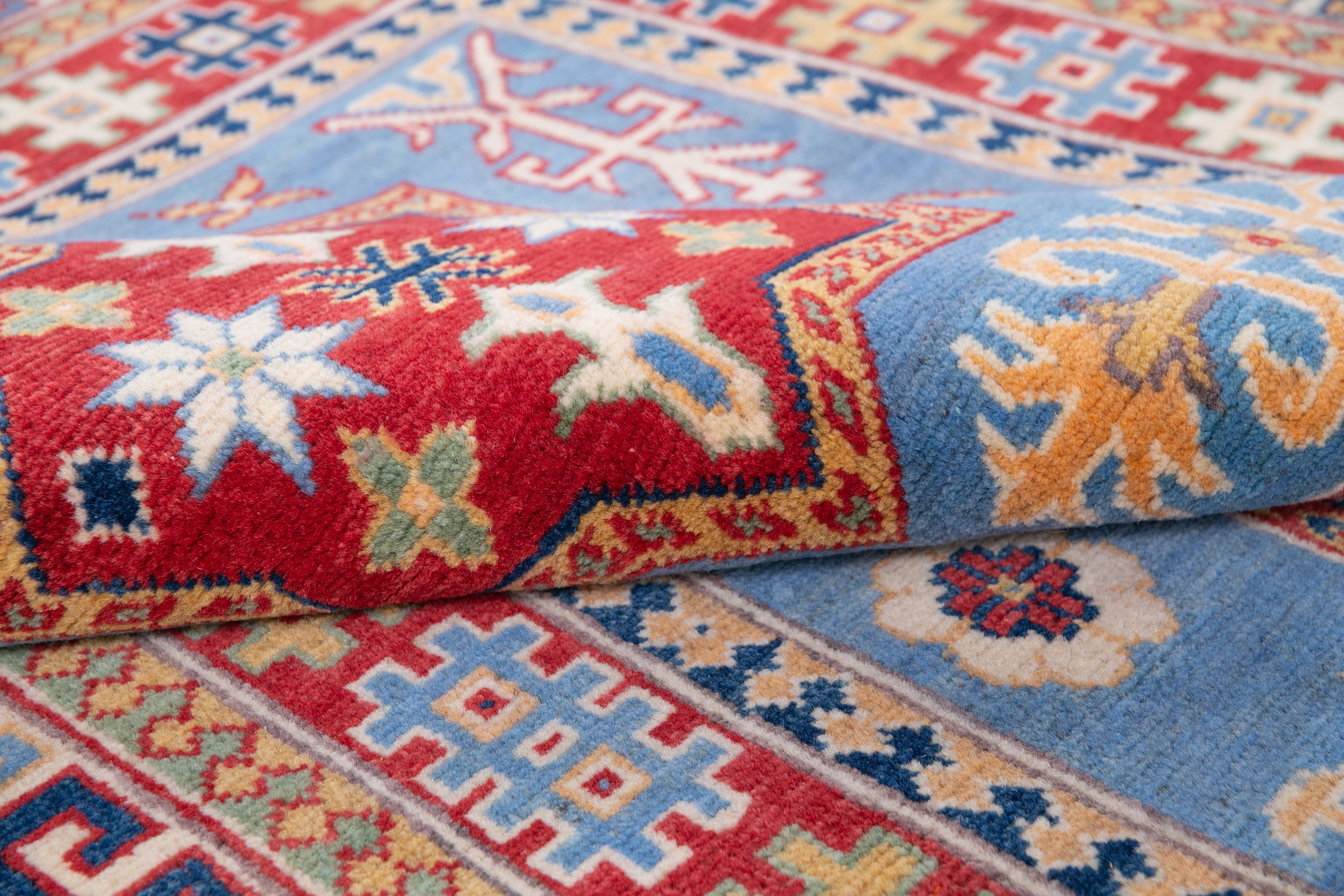 Folded edge and wool pile of blue & red Kazak-inspired wool rug 22077.