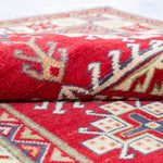 Folded edge and wool pile of red & ivory Kazak-inspired wool rug 23925.
