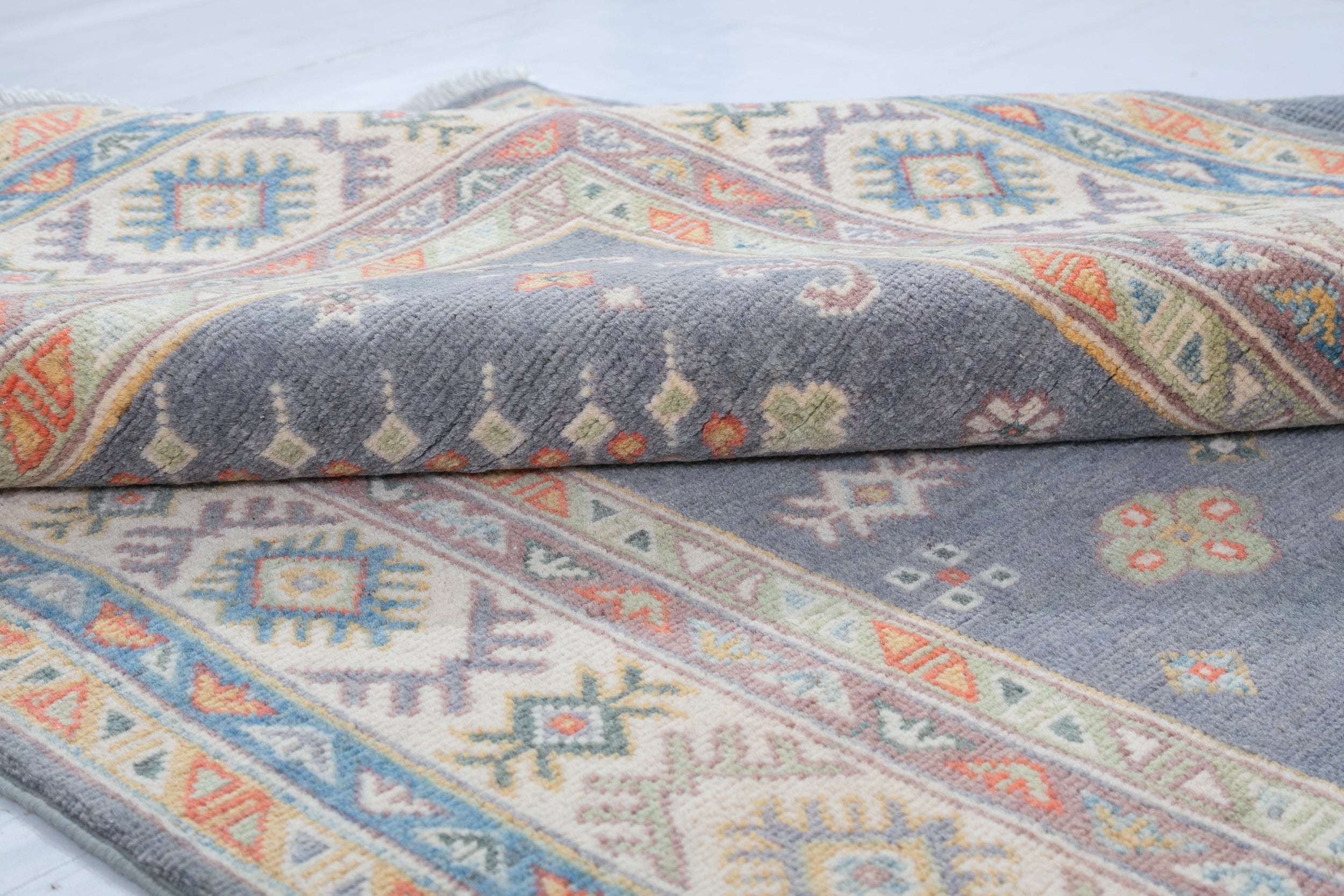 Folded edge and wool pile of blue & ivory Kazak-inspired wool rug 26753.