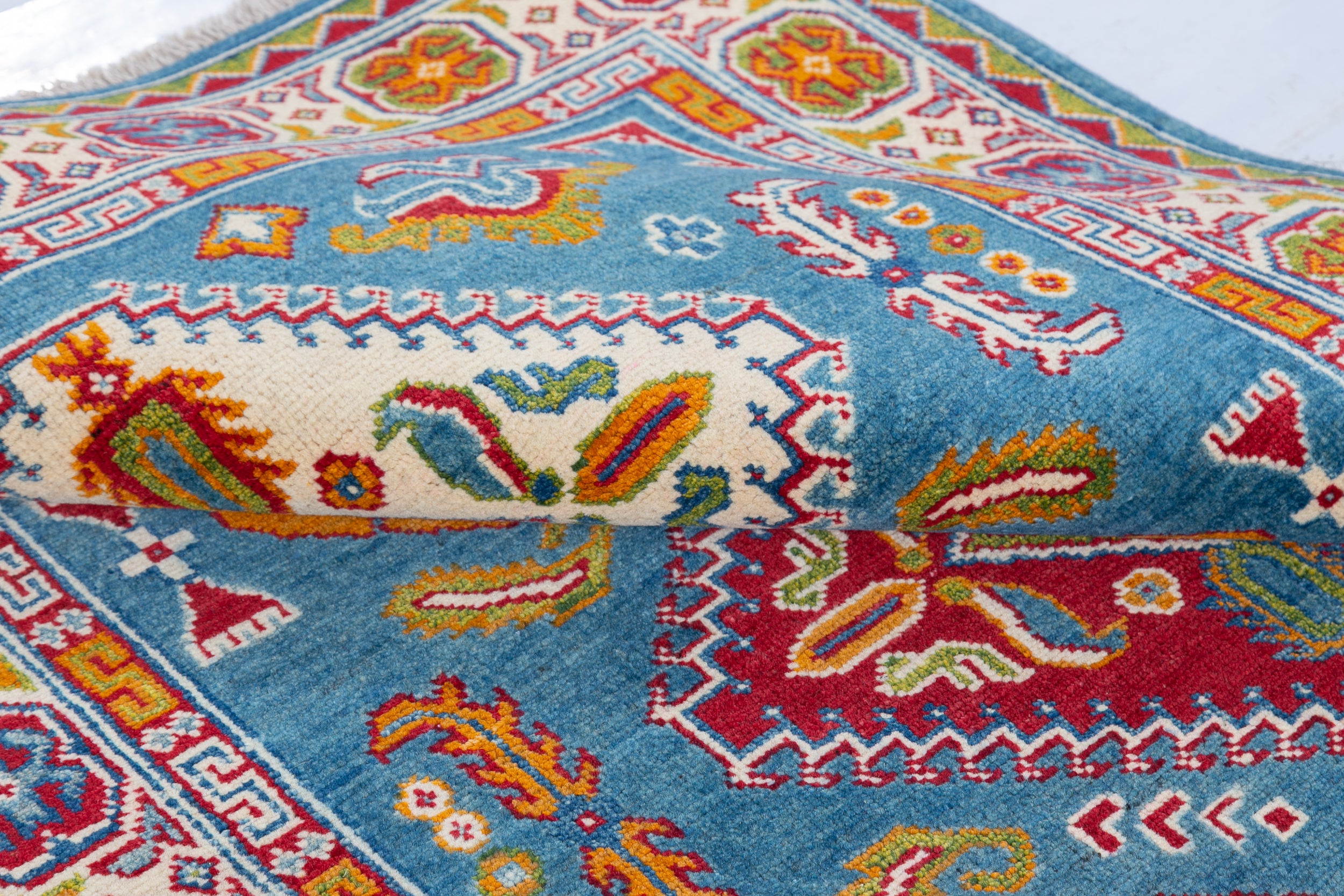 Folded edge and wool pile of blue & red Kazak-inspired wool rug 27434.