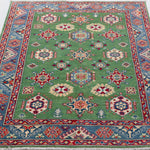 Full view from a low angle of green & red Kazak-inspired wool rug 29347.