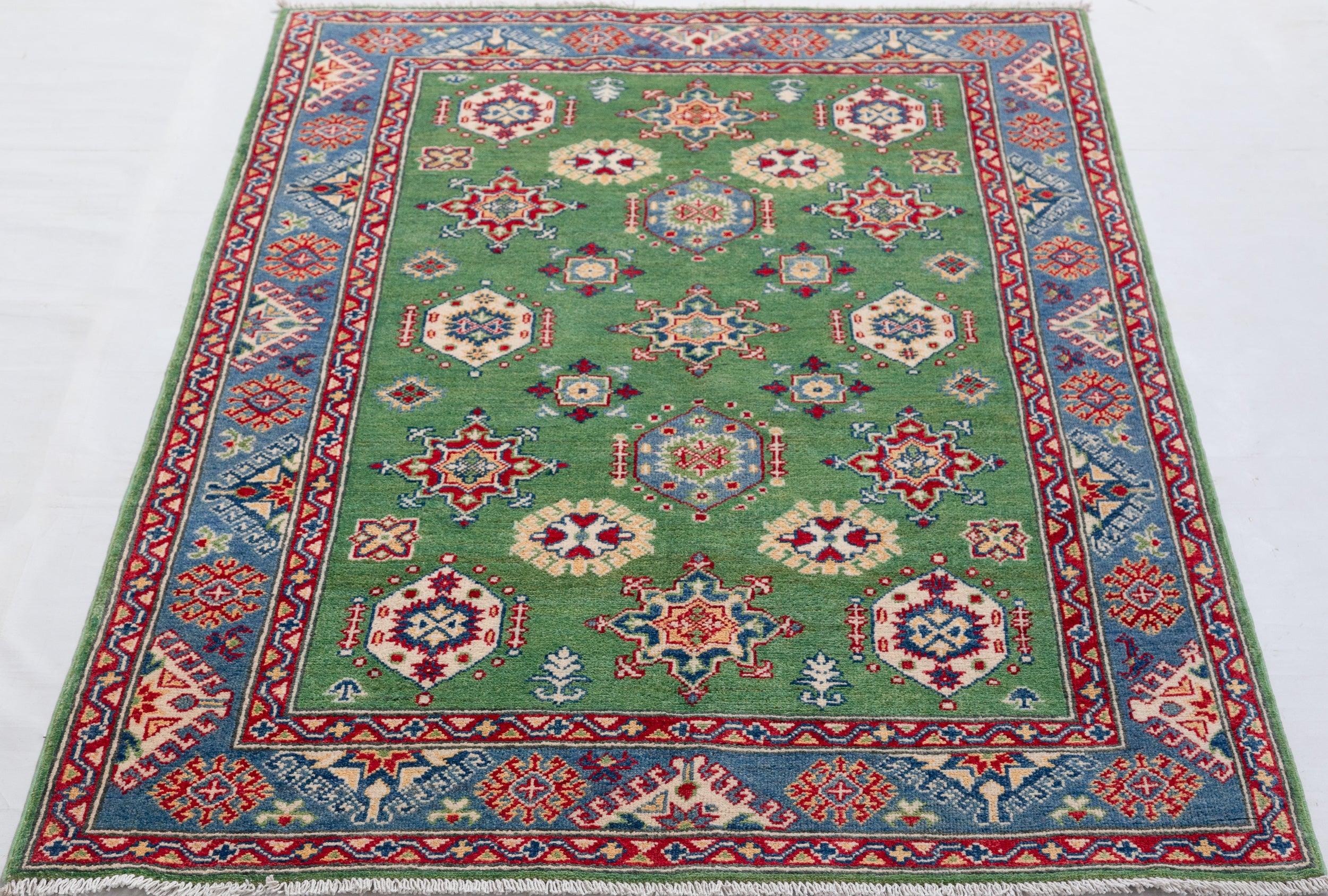 Full view from a low angle of green & red Kazak-inspired wool rug 29347.