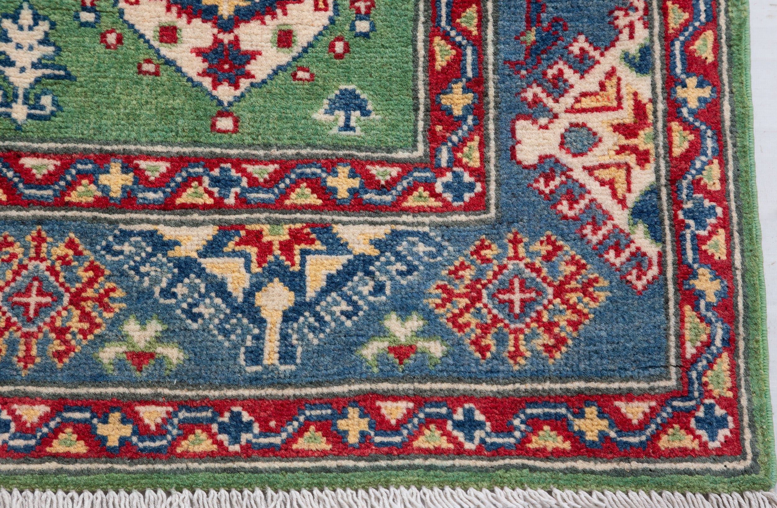 Border and edge detail of green & red Kazak-inspired wool rug 29347.