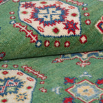 Folded edge and wool pile of green & red Kazak-inspired wool rug 29347.