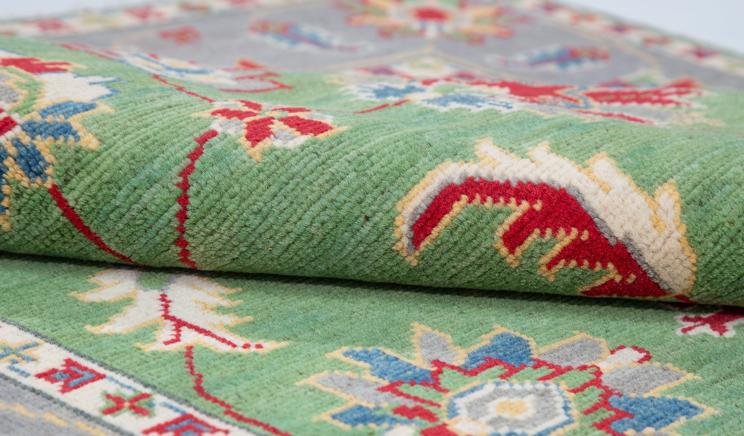 Folded edge and wool pile of green & ivory Kazak-inspired wool rug 29646.