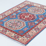 Full view at an angle of blue & red Kazak-inspired wool rug 29648.