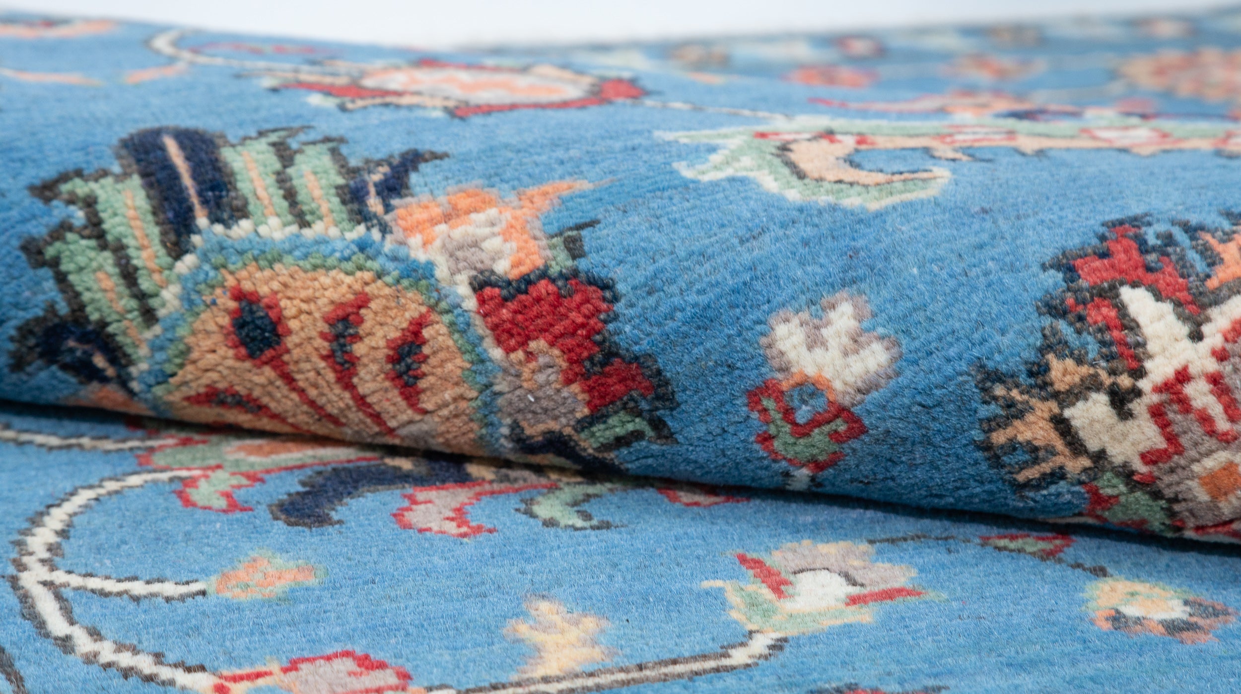 Folded edge and wool pile of blue & red Kazak-inspired wool rug 29649.