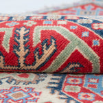 Folded edge and wool pile of ivory & red Kazak-inspired wool rug 29652.