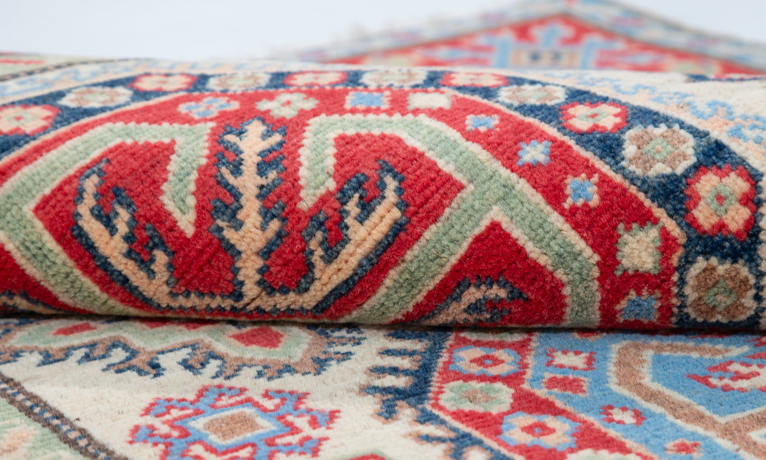 Folded edge and wool pile of ivory & red Kazak-inspired wool rug 29652.