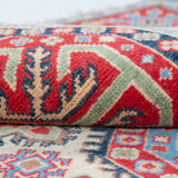 Folded edge and wool pile of ivory & red Kazak-inspired wool rug 29652.