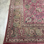 Persian Tabriz rug corner detail with dusty rose ground, cream vines, and fringed edge
