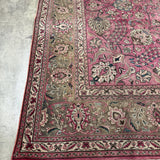 Persian Tabriz rug corner detail with dusty rose ground, cream vines, and fringed edge