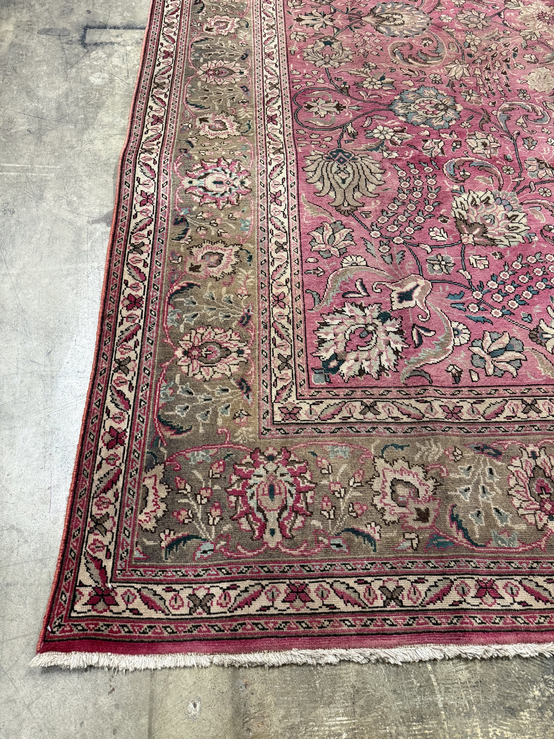 Persian Tabriz rug corner detail with dusty rose ground, cream vines, and fringed edge