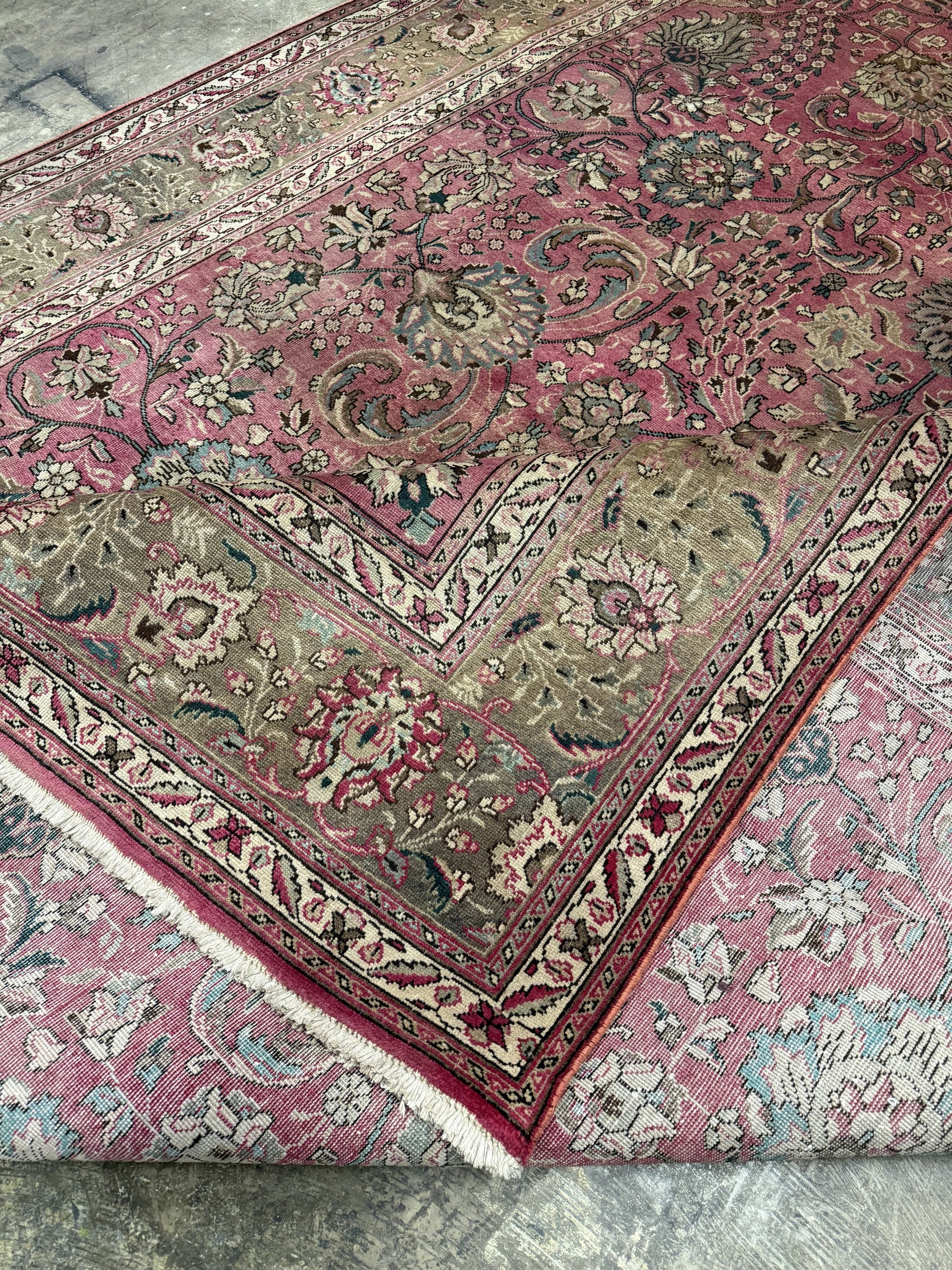 Persian Tabriz rug angled view with dusty rose layout, ivory border, and dense floral design