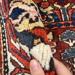 Vintage Shalamzar Bakhtiari Wool Rug, close-up of pile and folded edge held by a hand. Hand digitally edited with AI; SKU EE 32215; source IMG_7428.