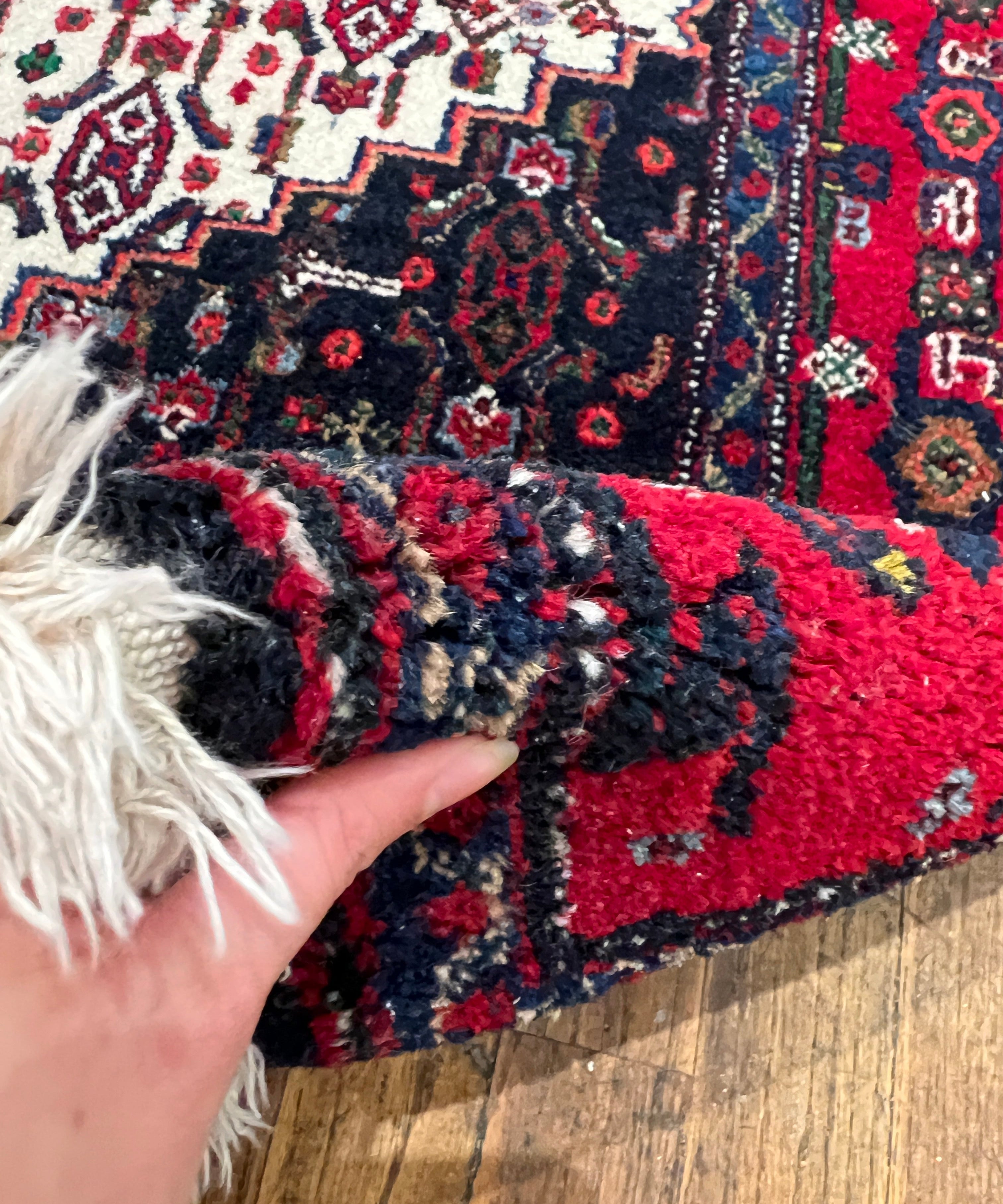 Persian Senneh rug corner with cream fringe and red-and-navy geometric pattern