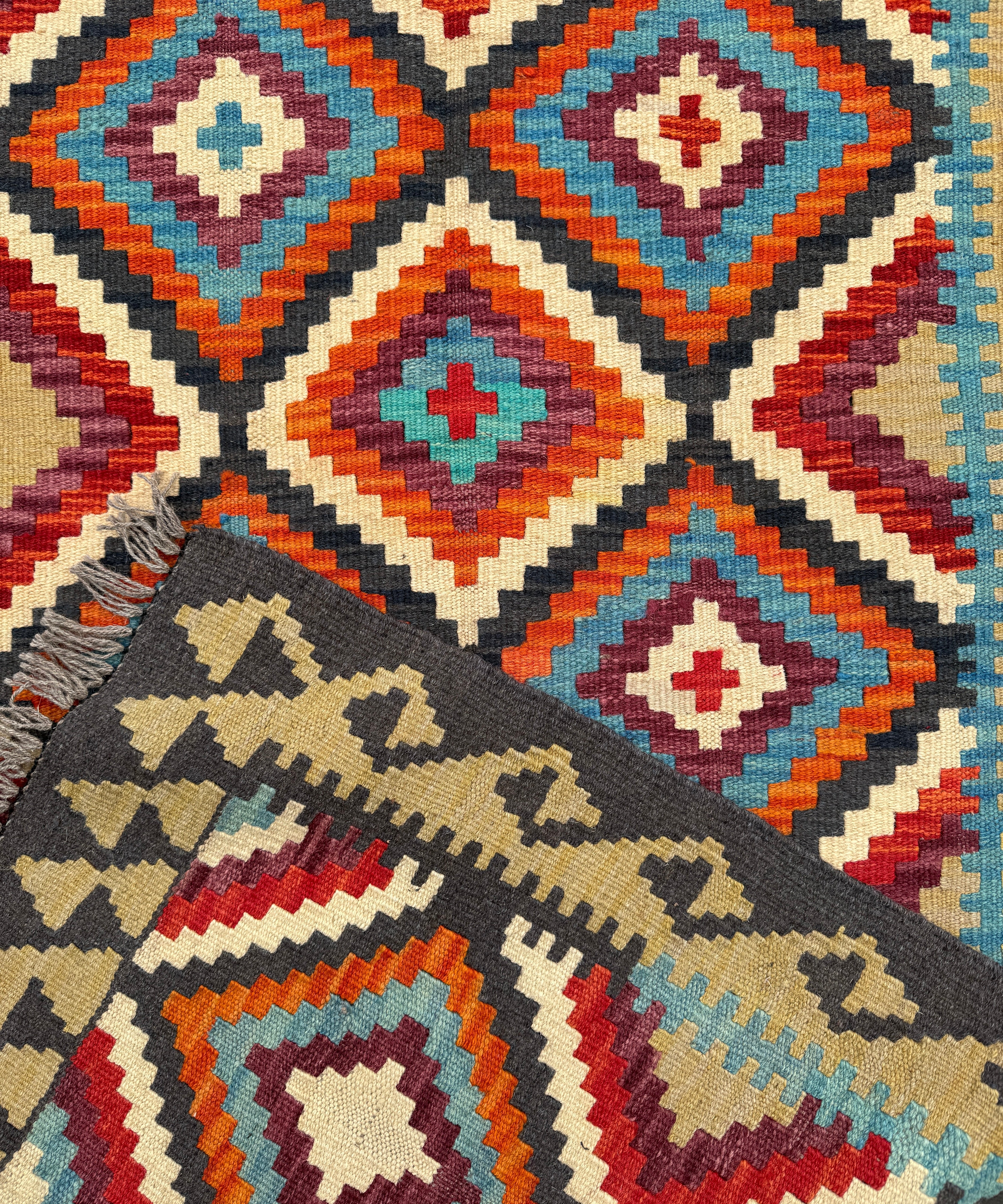 Kilim runner rug with multicolor diamond medallion pattern and dark border, close-up