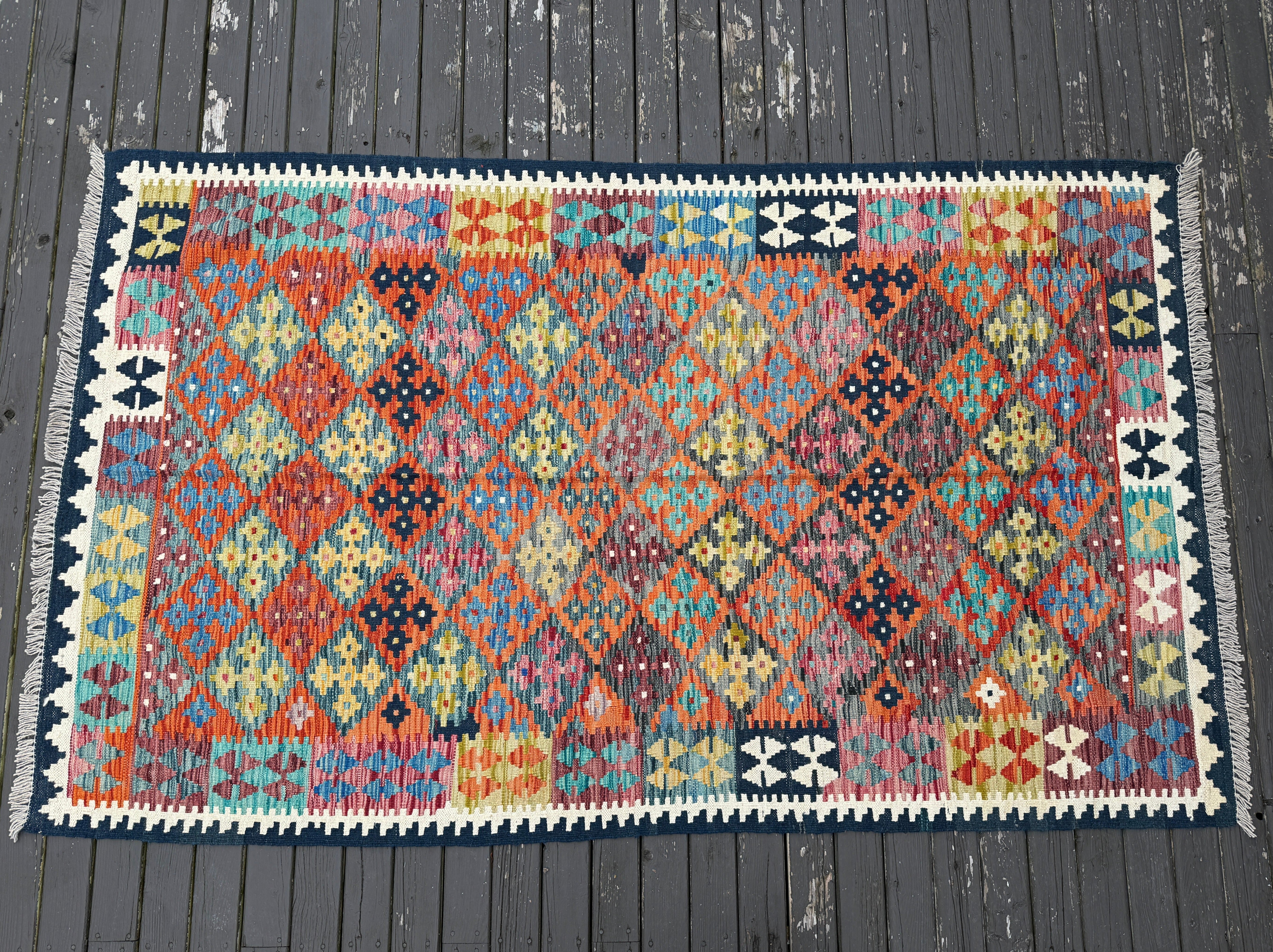 Multicolor Afghan kilim rug with diamond geometric pattern and dark navy border.