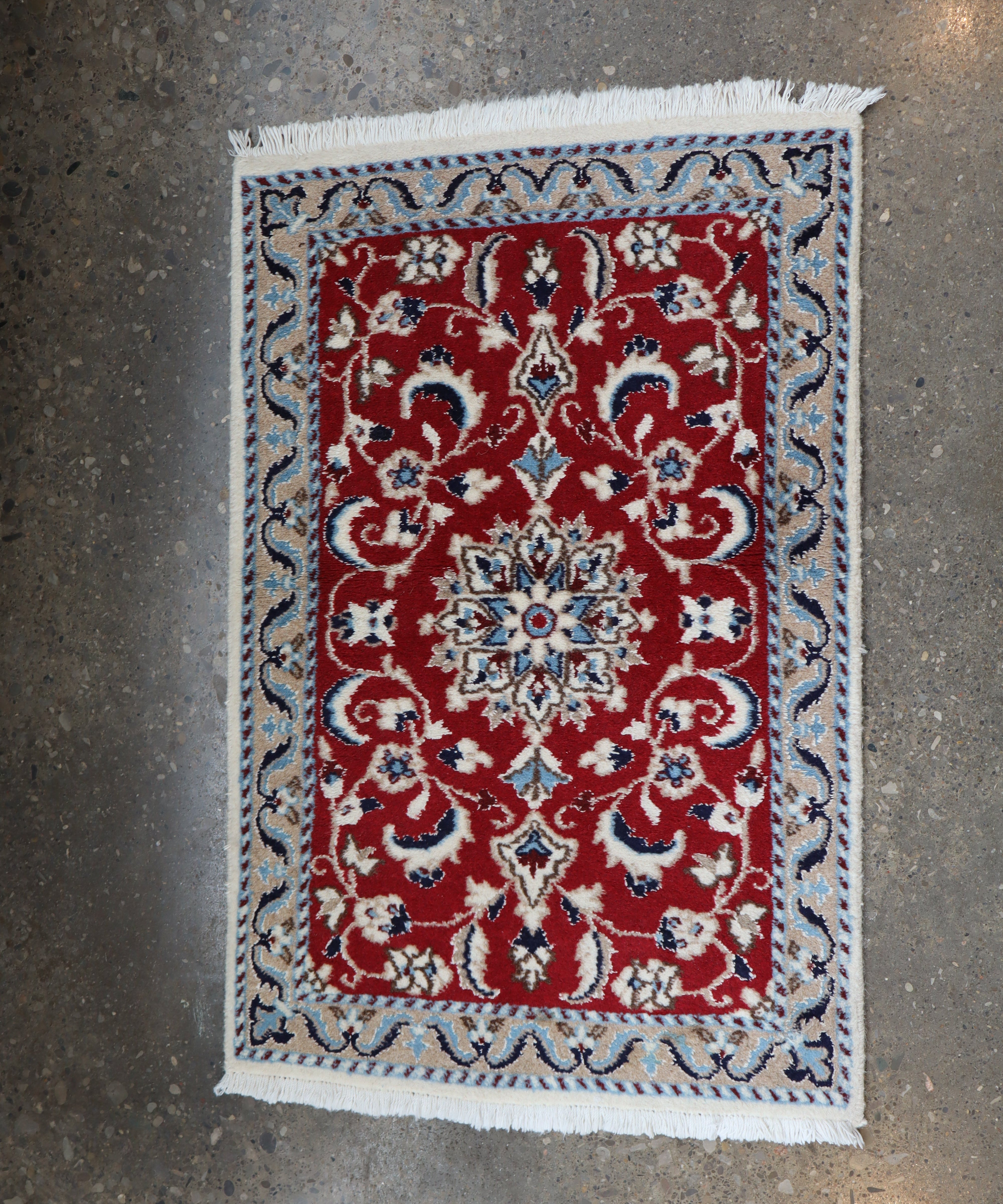 Persian Nain rug with red floral center panel and light-blue border, fringed corners