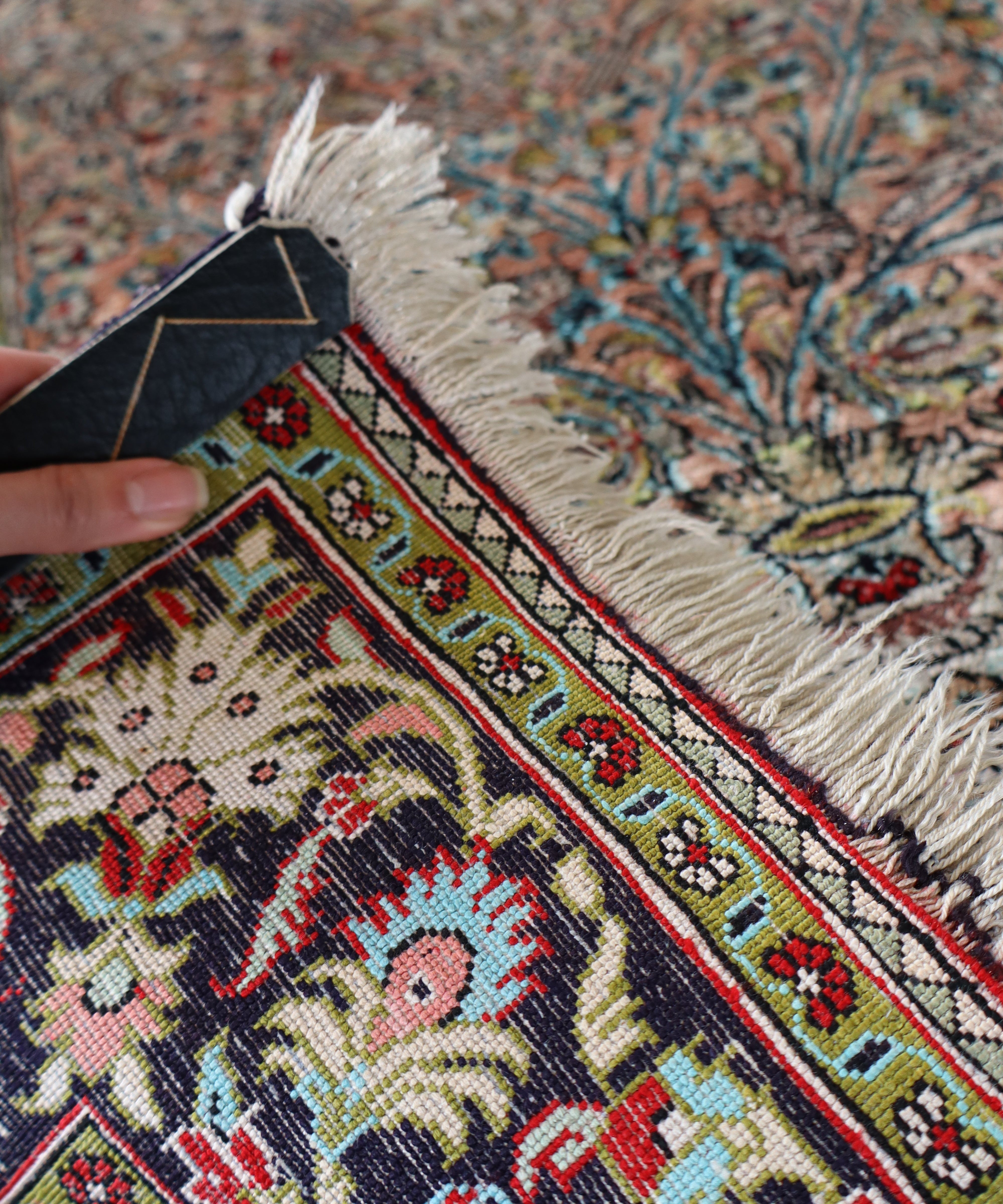Persian Qum silk rug corner detail with fringe fibers and small geometric motifs