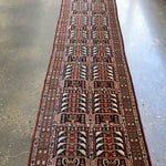 Afghan runner rug with navy, red, and cream geometric medallion border design.