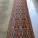 Afghan runner rug with navy, red, and cream geometric medallion border design.