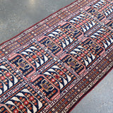 Afghan runner rug runner rug angled view with navy, red, and cream repeating rows.