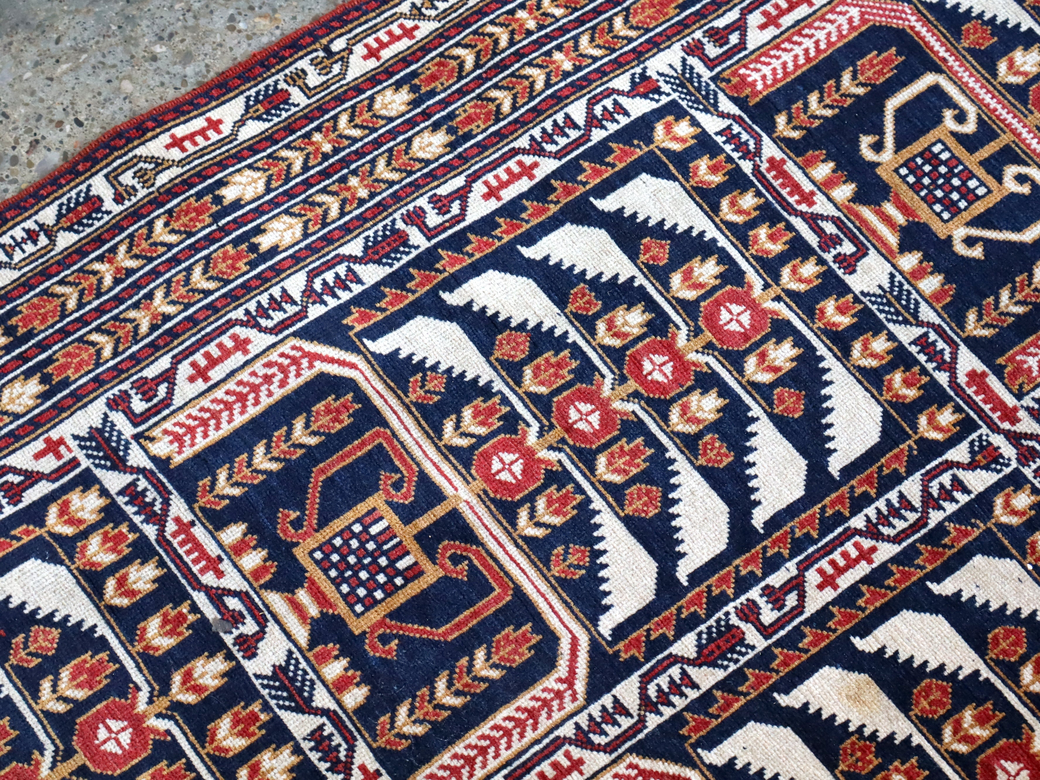 Afghan runner rug close-up of navy, red, and cream geometric motifs and borders.