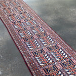 Afghan runner rug angled full view with navy, red, and cream ornamental panels.