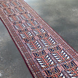 Afghan runner rug angled full view with navy, red, and cream ornamental panels.