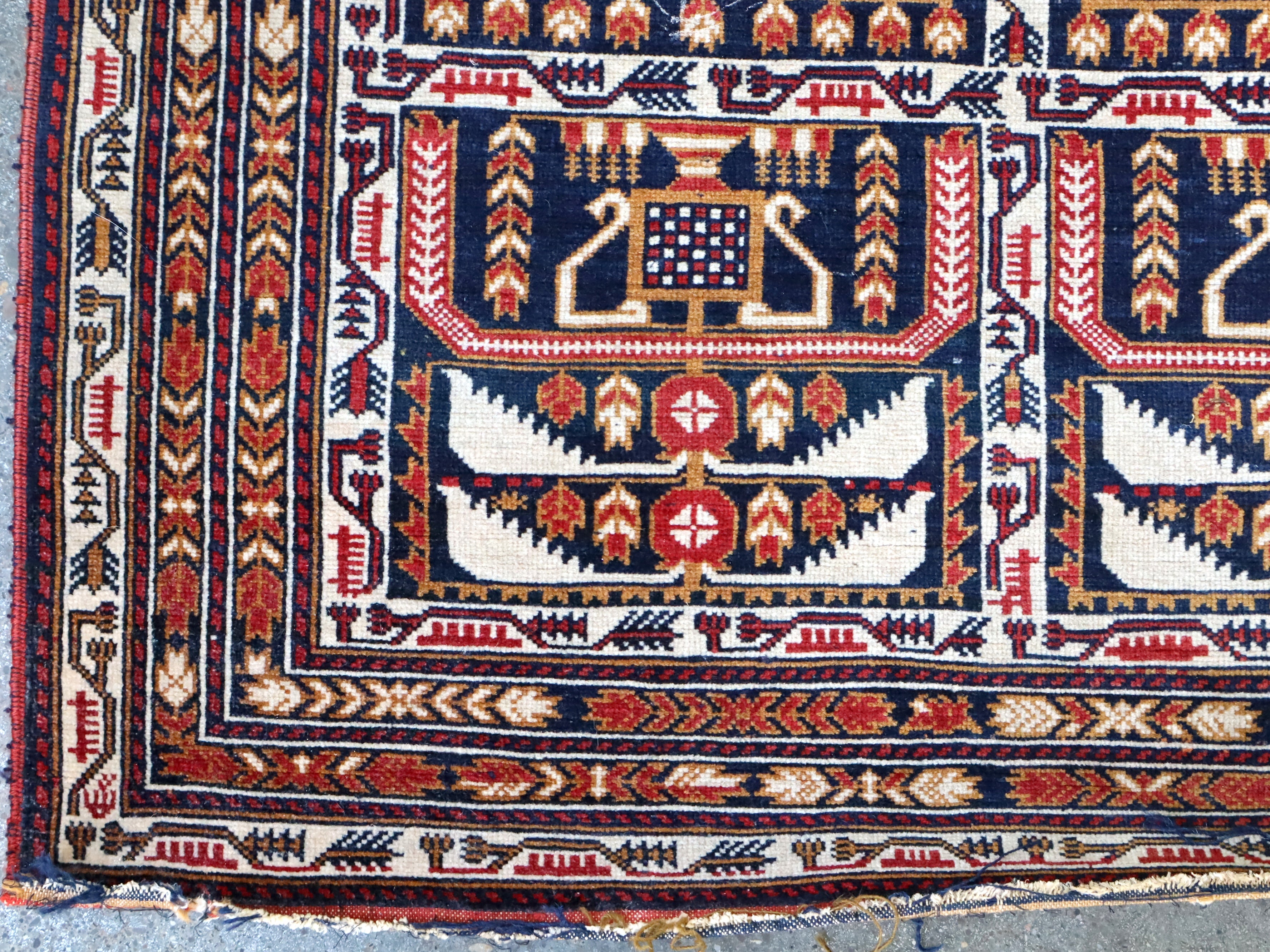 Afghan runner rug close-up of central navy and red framed motifs on cream background.