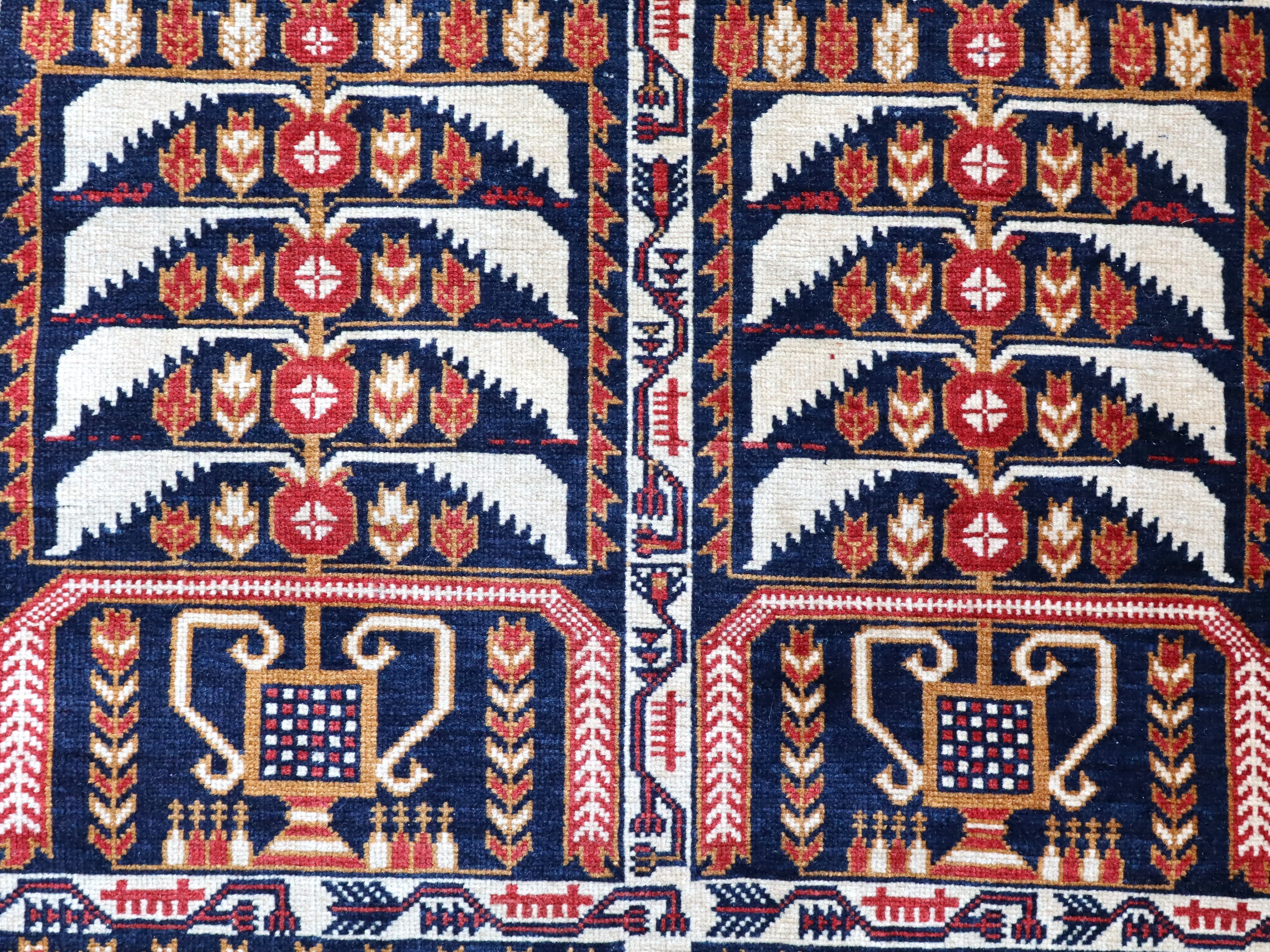 Afghan runner rug close-up of two navy-red panels with cream arches and tulip motifs.