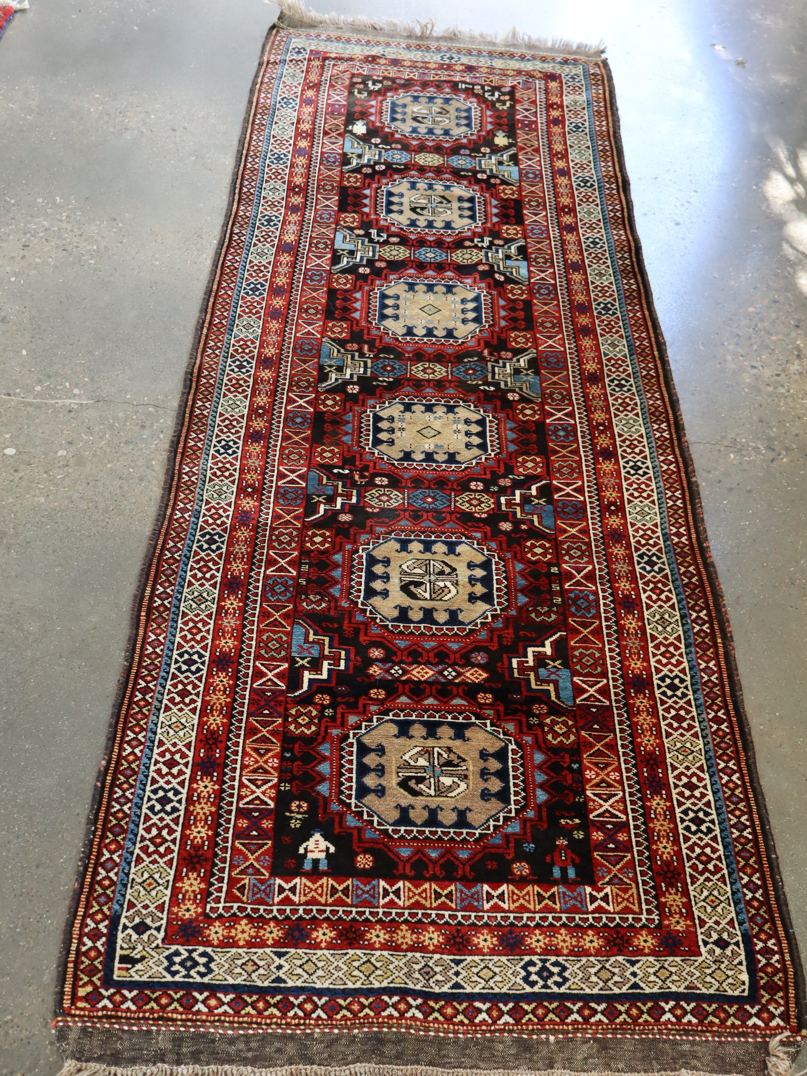 Semi-antique runner rug with red, black, and blue medallion pattern and border