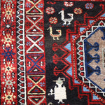 Semi-antique runner rug detail of red side strip and blue medallion on dark background