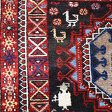 Semi-antique runner rug detail of red side strip and blue medallion on dark background