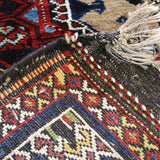 Semi-antique runner rug corner close-up with braided trim and multicolor motifs