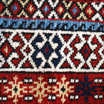 Runner rug decorative border with blue, red, cream and navy diamond and zigzag motifs.