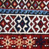 Runner rug decorative border with blue, red, cream and navy diamond and zigzag motifs.