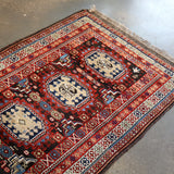 Runner rug flat on concrete floor with red central medallions and blue geometric accents.