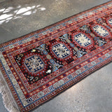 Runner rug wide view with red field, multiple blue medallions, and fringe at ends.