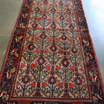 Rectangular area rug with light background, red accents, blue medallion pattern, dark border
