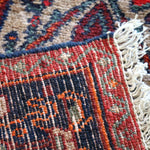Rug edge with woven fringe and multicolor stripe band in red, blue, and cream